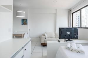 un salon blanc avec une télévision et un canapé dans l'établissement Conforto e praticidade em Boa Viagem., à Récife