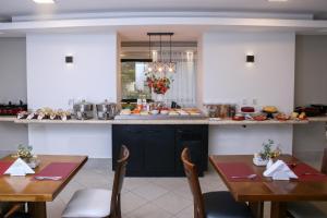 a kitchen with two tables and a counter with food at Marsala Apart Hotel in Mogi das Cruzes