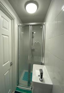 a white bathroom with a shower and a sink at Stadium Nook in Wembley