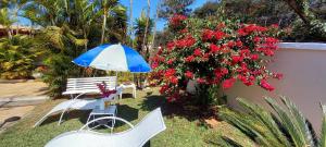 un patio con sillas, sombrilla y flores en Casa Pampulha, en Belo Horizonte