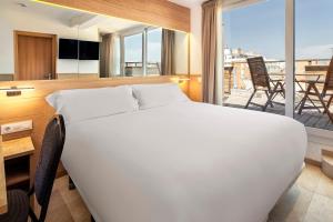 Cama blanca grande en habitación con balcón en B&B HOTEL Tarragona Centro Urbis, en Tarragona