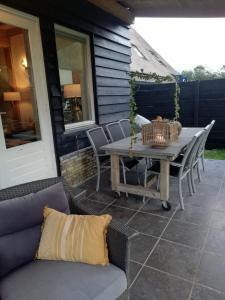 a patio with a table and chairs on a house at Vakantiehuis Idylle aan Zee, privé SAUNA in Sint Maartensvlotbrug