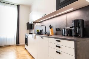 uma cozinha com armários brancos e electrodomésticos pretos em Apartment Erdberg I contactless check-in em Viena