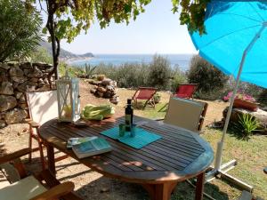 un tavolo in legno con una bottiglia di vino e un ombrello di Ariadimare guest house a Finale Ligure