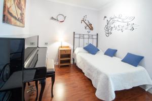 a bedroom with two beds with blue pillows and a piano at Apartamento El Pentagrama de Cádiz in Cádiz