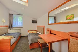 Pokój z 2 łóżkami, biurkiem i lustrem w obiekcie Willa Mak w mieście Krynica Zdrój