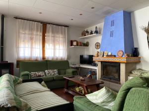 sala de estar con 2 sofás verdes y chimenea en Ca Ramonet, en Arañuel