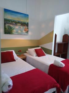 um quarto com 2 camas com lençóis vermelhos e brancos em Estação Caraíva em Caraíva