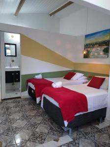 a bedroom with two beds with red and white sheets at Estação Caraíva in Caraíva