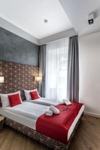 a bedroom with a large bed with red pillows at Apartamenty Nowa Kamienica Częstochowa Centrum Szymanowskiego 22A in Częstochowa