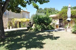 einen Garten vor einem Haus mit Sonnenschirm in der Unterkunft Luc et Corine in Saint-Restitut