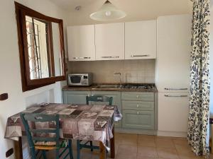 cocina con mesa con sillas y microondas en Residence La Conia, en Cannigione