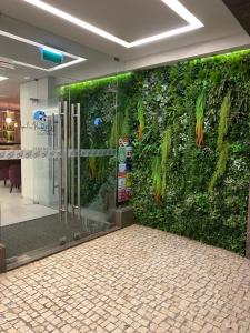 a green wall in a lobby with a glass door at Apulia Praia Hotel in Esposende