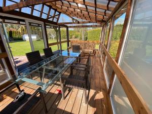 a screened in porch with a glass table and chairs at Skujas in Saulkrasti