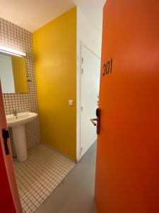 una puerta de color naranja al baño con lavabo en Auberge de Jeunesse HI Lille, en Lille