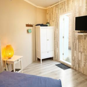 um quarto com uma cama, uma cómoda e uma televisão em Pension Pitstop em Zandvoort