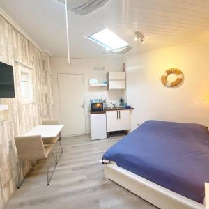 a bedroom with a bed and a table and a kitchen at Pension Pitstop in Zandvoort
