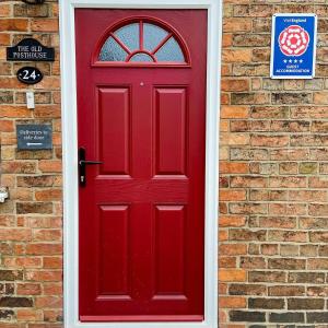 eine rote Tür an einer Ziegelmauer mit einem Schild in der Unterkunft The Old Posthouse B&B in Caenby