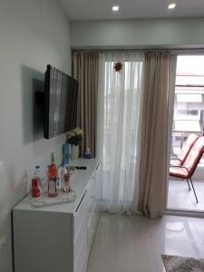 a living room with a flat screen tv on a dresser at M & M White Luxury in Paralia Katerinis