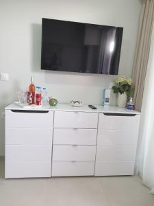 a white cabinet with a flat screen tv on a wall at M & M White Luxury in Paralia Katerinis