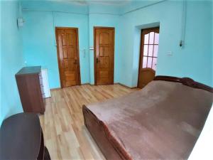 a bedroom with a bed and wooden floors and blue walls at Затишна квартира в центрі Калуша in Kalush