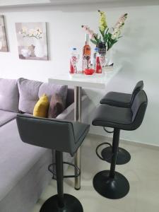 a table and two stools next to a couch at M & M White Luxury in Paralia Katerinis