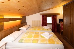 two beds in a room with wooden ceilings at Residence San Marco by Alpenwhite in Livigno