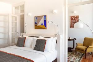 a bedroom with a bed, chair, mirror and a painting on the wall at Casa Balthazar in Lisbon