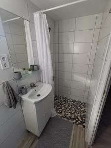 La salle de bains blanche est pourvue d'un lavabo et d'une douche. dans l'établissement Vali néni kifőzde és apartman, à Kismaros