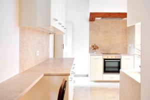 uma cozinha com armários brancos e um forno com placa de fogão em Casa Balthazar em Lisboa