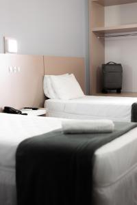 a room with three beds and a suitcase at Rede Andrade Cecomtur in Florianópolis