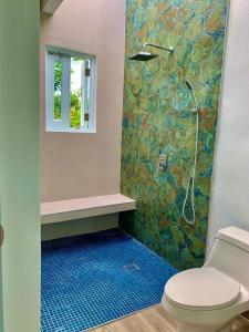 a bathroom with a shower with a toilet and a blue floor at Villa del Carmen Boqueron in Cabo Rojo