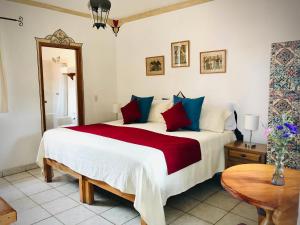 a bedroom with a large bed with red and blue pillows at Hotel Casa Blanca in Ajijic