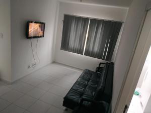 a living room with a black leather couch and a television at Pausa da Correria nesta estadia I in Caraguatatuba