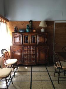 a wooden cabinet in a room with chairs and a table at Cruz del Sur in Pinamar