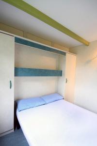 a bedroom with a white bed with a blue headboard at Camping La Rueda in Cubelles