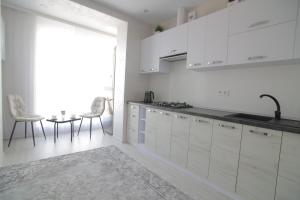 a kitchen with white cabinets and a table with chairs at Ніжність in Rivne