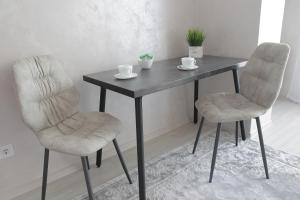 stół z dwoma krzesłami i stół z dwoma kubkami w obiekcie Ніжність w mieście Rivne