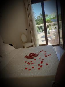 una camera da letto con un letto con petali di rosa rosso sopra di Tenuta Ippocrate a Montefredane