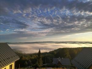 a view of a foggy valley with buildings and trees at Górskie domki w Karkonoszach z widokiem in Podgórzyn