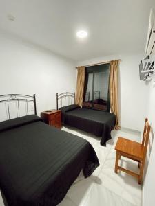 1 dormitorio con 2 camas, silla y ventana en HOSTAL EL MOLINO, en Marbella
