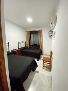 una habitación de hotel con 2 camas y una silla en HOSTAL EL MOLINO, en Marbella