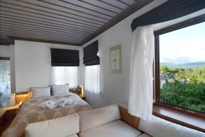 a bedroom with a bed and a large window at Dilofo Hotel Luxury Suites in Dilofo