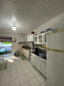 a large kitchen with white cabinets and a refrigerator at Rancho Manacá in Guaramiranga