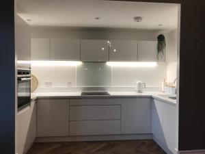 a white kitchen with white cabinets and appliances at Argyll Square Apartment Oban in Oban