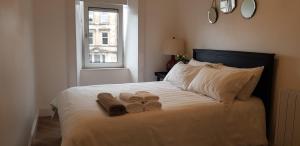 a bedroom with a bed with two towels and a window at Argyll Square Apartment Oban in Oban
