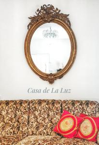 een spiegel boven een bank met twee kussens bij Casa de la Luz in Navas de Oro