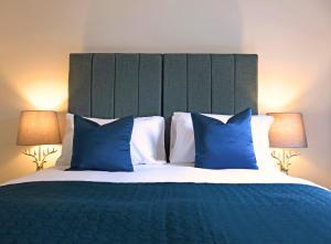 a bedroom with a large bed with blue pillows at Gleneagles Luxury Apartment in Auchterarder