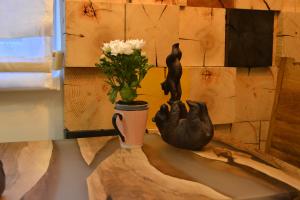 a table with a vase of flowers and a cat statue at Olimpijska kuca Jahorina - Apartman A708 in Jahorina +38 photos
