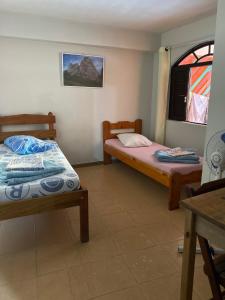 two beds in a room with a window at Pousada Serra Carioca Friburgo in Nova Friburgo